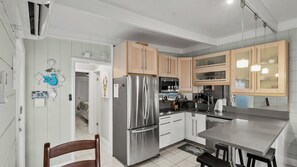 A modern kitchen with stainless steel appliances, wooden cabinets, and a dining area with a table and chairs. - P15 - Waterfront, ground level duplex with Cabana Club (Key Colony Beach)