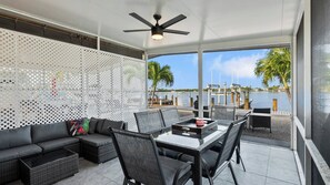 A modern outdoor seating area with a table and chairs, a sofa, and a decorative lattice wall. - P15 - Waterfront, ground level duplex with Cabana Club (Key Colony Beach)