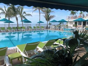 A pool area with lounge chairs and umbrellas, surrounded by palm trees. - P15 - Waterfront, ground level duplex with Cabana Club (Key Colony Beach)