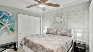 A bedroom with a bed, a ceiling fan, a nightstand, and a wall with a starfish decoration. - P15 - Waterfront, ground level duplex with Cabana Club (Key Colony Beach)