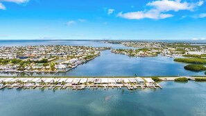 An aerial view of a marina with boats docked, surrounded by residential buildings and greenery. - P15 - Waterfront, ground level duplex with Cabana Club (Key Colony Beach)