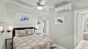 A bedroom with a bed, a ceiling fan, an air conditioning unit, and artwork on the walls. - P15 - Waterfront, ground level duplex with Cabana Club (Key Colony Beach)