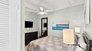 A bedroom with a bed, a dresser, a television, a mirror, and a painting on the wall. - P15 - Waterfront, ground level duplex with Cabana Club (Key Colony Beach)