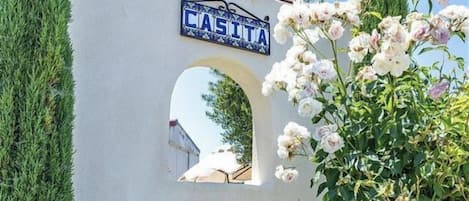 Pared blanca con un letrero azul que dice 'CASITA' sobre un ventanal arqueado.