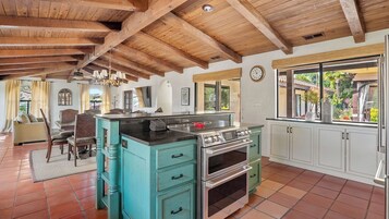 Una cocina con una isla central, vigas de madera en el techo y vistas al exterior.