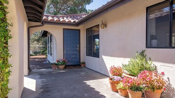 Una casa con puerta azul, un porche cubierto y macetas con plantas.