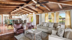 A spacious living area with a high ceiling, a dining area with a brick wall, and a kitchen with white cabinets. - Hacienda Buena Vida by Avantstay Gated Casita + BBQ Courtyards Wine Country (Templeton)