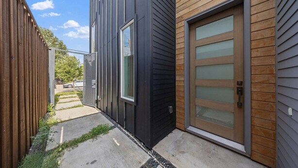 Et moderne hus med mørk facade, en trædør med sandblæst glas og en metalport.