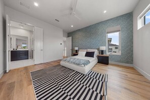 A modern bedroom with a bed, bedside tables, a window, and a patterned rug. - Modern Trinity Groves Home w/ Rooftop + Garage (Dallas)