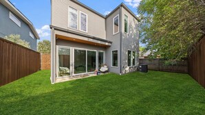 Et moderne hus med to etager, en velholdt græsplæne og et træhegn.