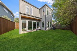 A modern two-story house with a well-maintained lawn and a wooden fence. - Modern Trinity Groves Home w/ Rooftop + Garage (Dallas)