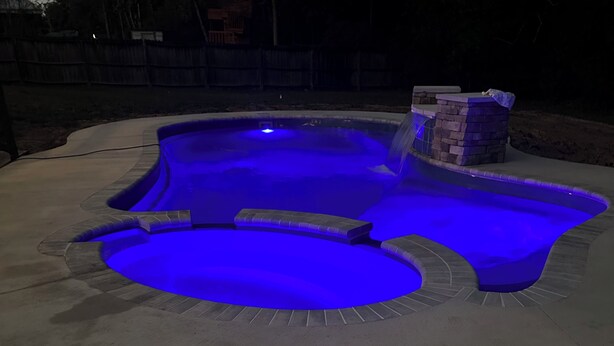 A swimming pool with a blue light feature, surrounded by a concrete deck. - Coastal  Serenity 3-bedroom house with heated pool and hot tub (Gulfport)
