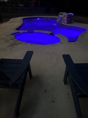 A swimming pool with a blue light feature, surrounded by a concrete deck. - Coastal  Serenity 3-bedroom house with heated pool and hot tub (Gulfport)