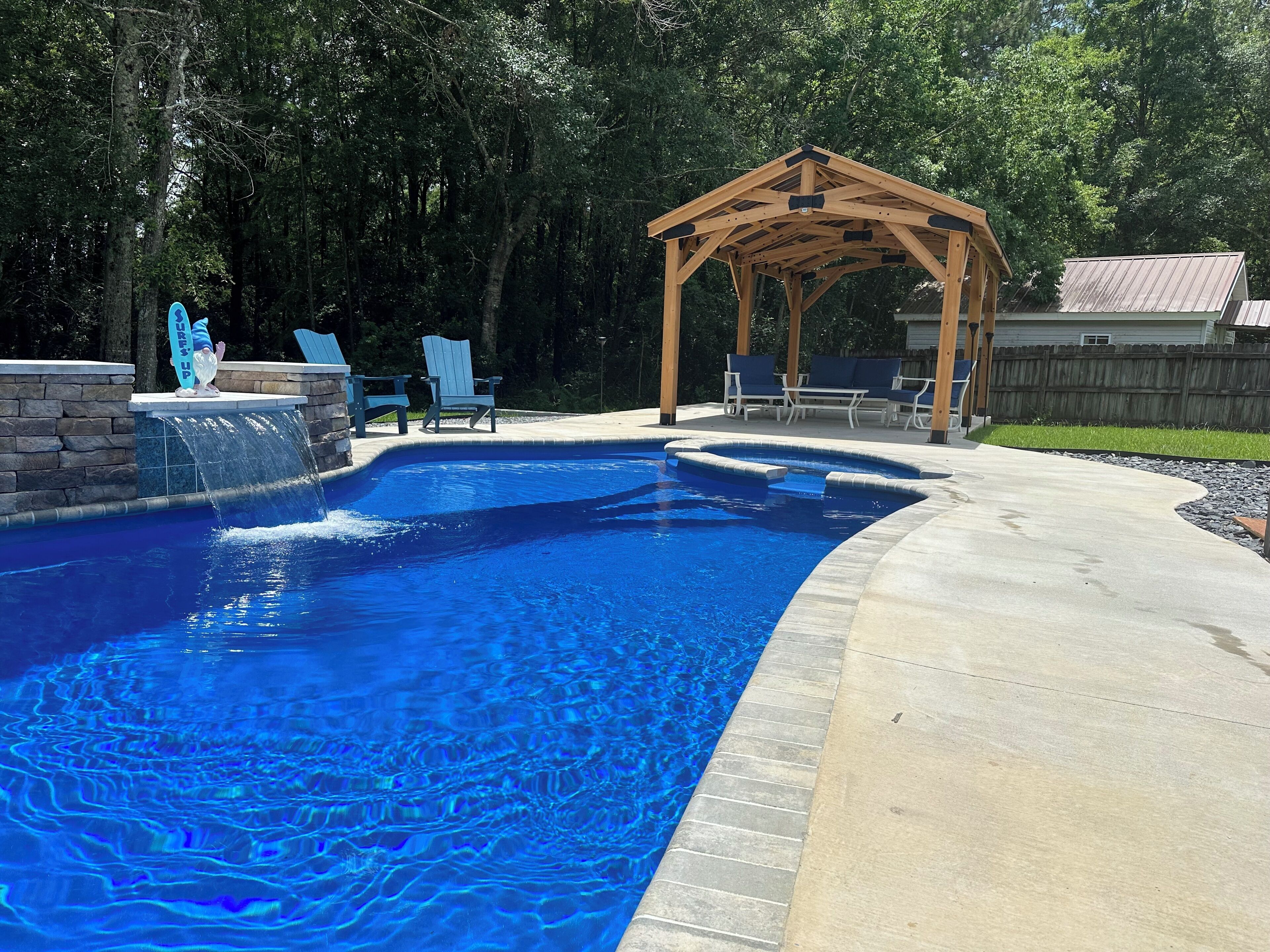 A swimming pool with a wooden pergola and lounge chairs.