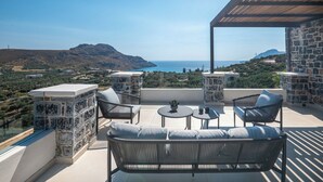 A terrace with a view of the sea, stone walls, and outdoor furniture.