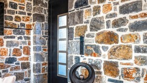 A room with a stone wall, a black door, and a white sofa.