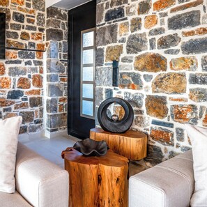 A room with a stone wall, a black door, and a white sofa. - Stone horizon villa (Myrthianos Plakias)