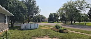 A residential street with houses, a swimming pool, and a well-maintained lawn.