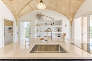 A kitchen with a central island, a built-in sink, and a hanging light fixture. - Lovely Villa w/ Pool & Garden, close to beaches (Pescoluse)