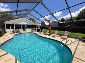 Ein Swimmingpool mit Liegestühlen und Sonnenschirmen, umgeben von einer überdachten Terrasse.