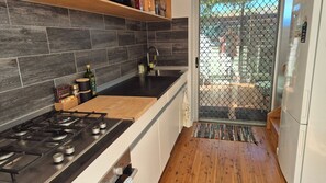 A kitchen with a gas stove, a sink, and a refrigerator. - Beachwood Villa - Modern Townhouse Walk to Beach (Crescent Head)