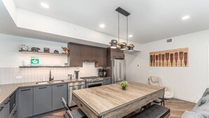 Una cocina moderna con gabinetes grises, una mesa de comedor de madera y un banco.