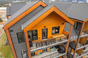 Ein mehrstöckiges Gebäude mit einem Balkon im zweiten Stock, mit Holzfassade und grauen Dachziegeln.