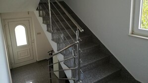 Eine Treppe mit Metallgeländern und dunklen Stufen, die zu einer Tür mit einem kleinen Fenster führt.