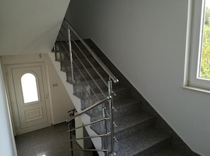 A staircase with metal railings and dark steps, leading to a door with a small window. - Beach Front Apartments Jasminka (Sibenik)