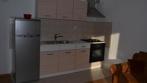 Eine kleine Küche mit Kühlschrank, Herd, Spüle und Schränken.