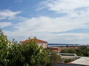 A residential area with houses, a clear sky, and a distant view of the sea. - Apartment Karma (Okrug)