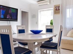 A dining area with a white round table, blue chairs, and a blue bowl. - Apartment Karma (Okrug)