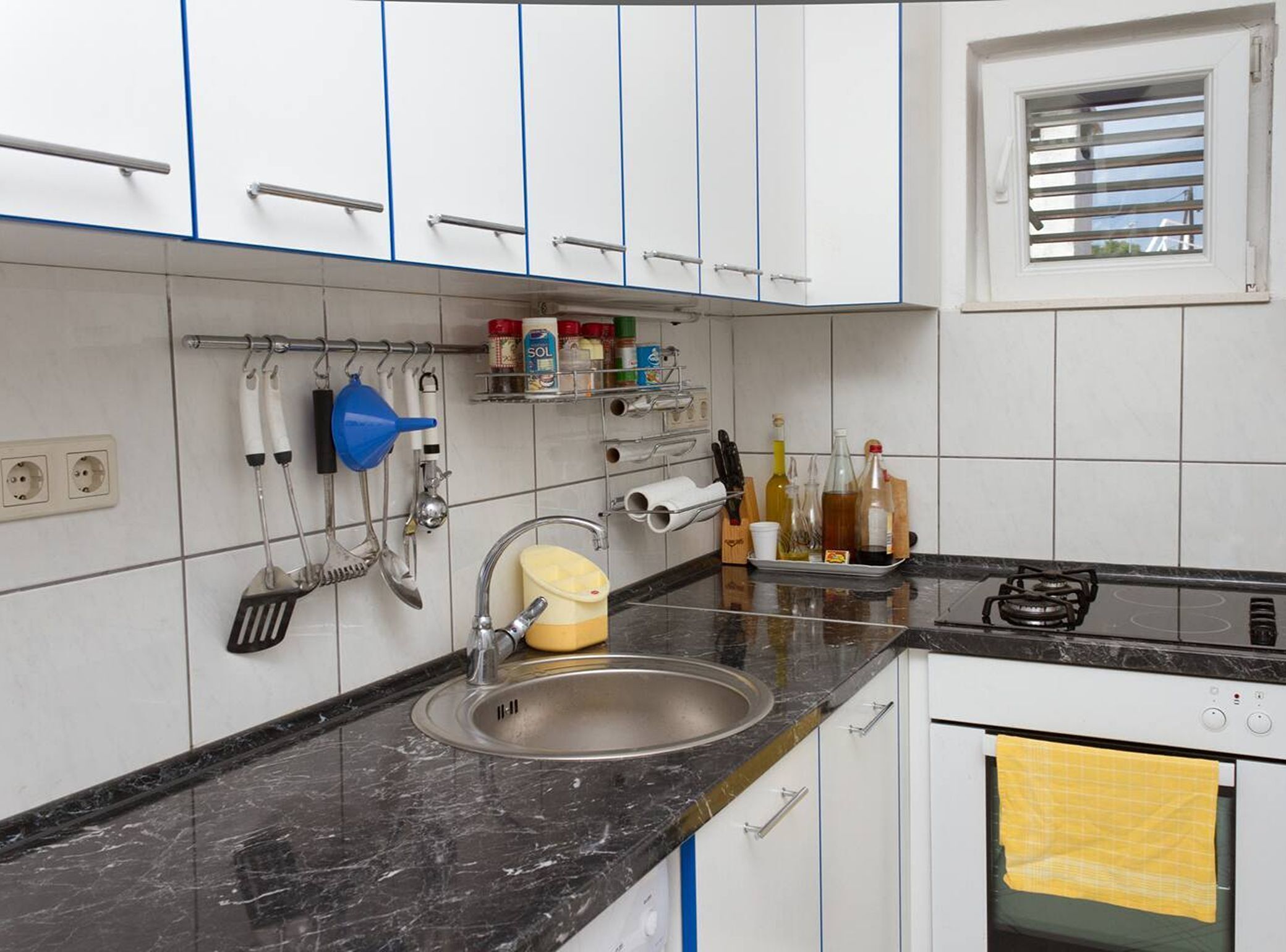 A kitchen with a sink, stove, and cabinets.