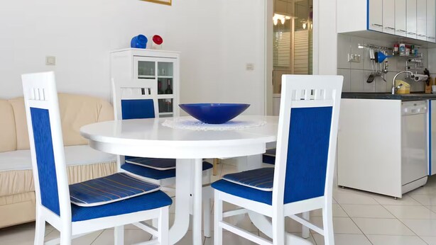 A compact living space with a dining area, kitchenette, and a sofa. - Apartment Karma (Okrug)