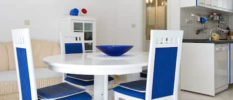 A compact living space with a dining area, kitchenette, and a sofa.