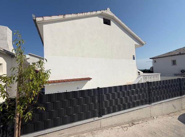 A building with a white exterior, a black fence, and a clear sky. - Apartment Karma (Okrug)