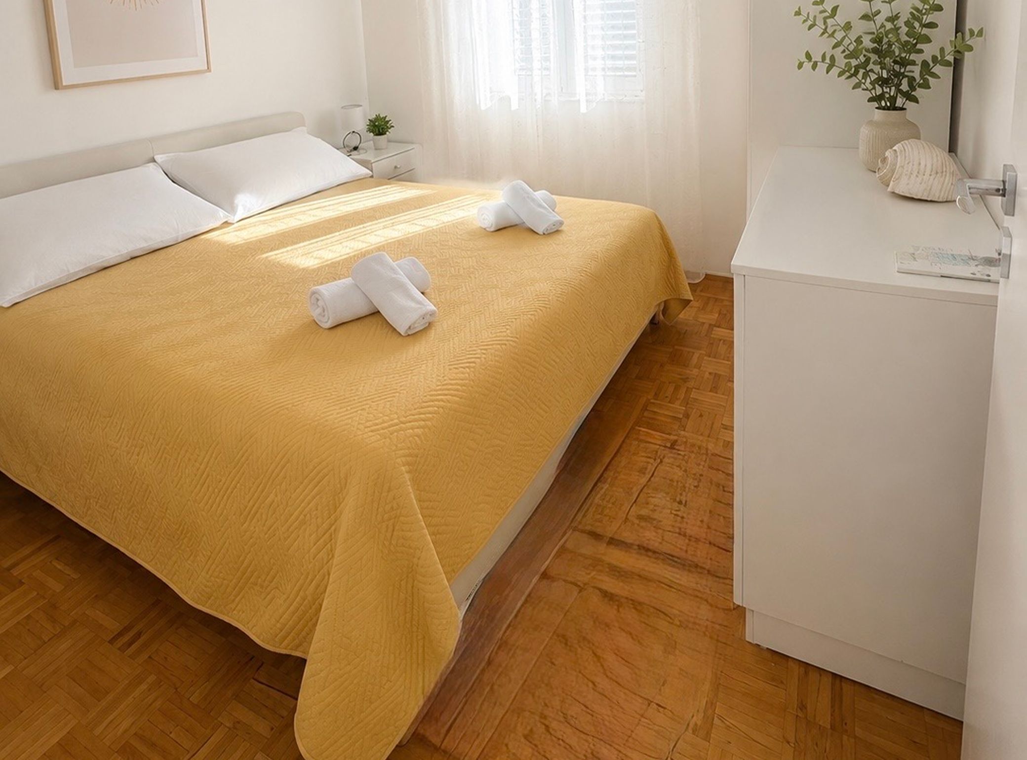Une chambre d’hôtel avec un lit, une table de chevet, une petite plante et une armoire blanche.