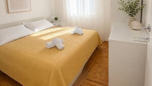 A hotel room with a bed, a nightstand, a small plant, and a white cabinet. - Apartment Karma (Okrug)