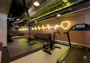 Ein Fitnessstudio mit Laufbändern, Kurzhanteln und Trainingsgeräten.