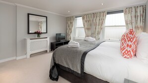 A modern bedroom with a bed, a TV, a dresser, and a window with curtains. - Two exclusive, neighbouring apartments sleeping 22 in Edinburgh’s historic centre. (Edinburgh)