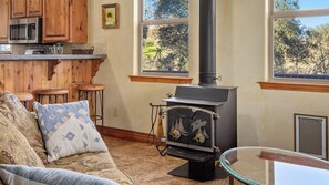 A cozy living room with a fireplace, wooden bar, and a sofa with patterned cushions. - Vita Amorosa by Avantstay Gated Cottage + Oak & Vineyard Views Near Paso Robles (Atascadero)