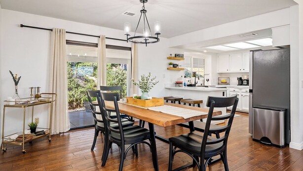 A modern kitchen with a dining area, wooden flooring, and a view of the outdoors. - Whispering Wine by Avantstay Country Acreage + Fire Pit + Deck Central Coast Wine Country (Paso Robles)