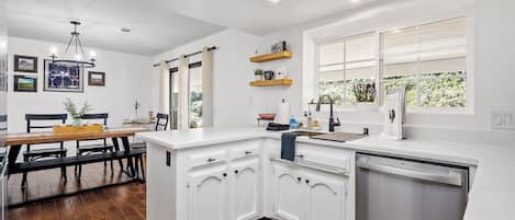 Una cocina moderna con armarios blancos, lavavajillas integrado y ventana con vistas a zonas verdes.