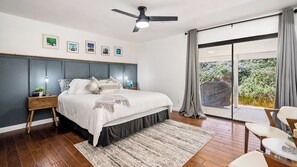 A bedroom with a bed, bedside tables, a ceiling fan, a large window with curtains, and a view of greenery outside. - Whispering Wine by Avantstay Country Acreage + Fire Pit + Deck Central Coast Wine Country (Paso Robles)