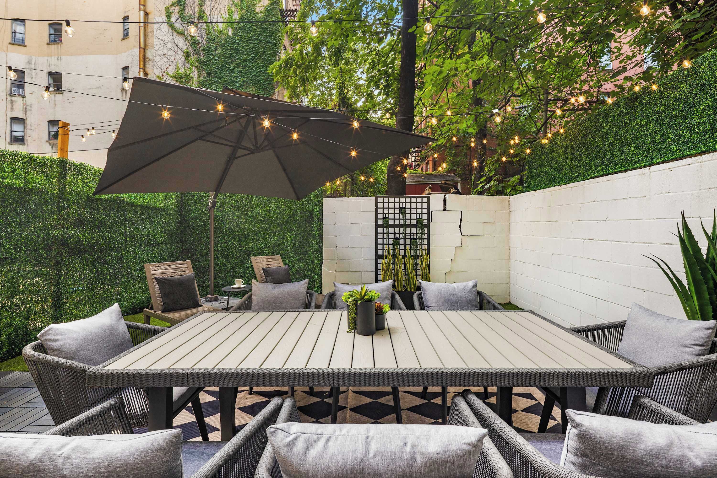 An outdoor patio with a wooden table, wicker chairs, and an umbrella.