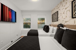 Hotellihuone, jossa on kaksi sänkyä, suuri abstrakti maalaus ja seeprankuvioinen seinä.