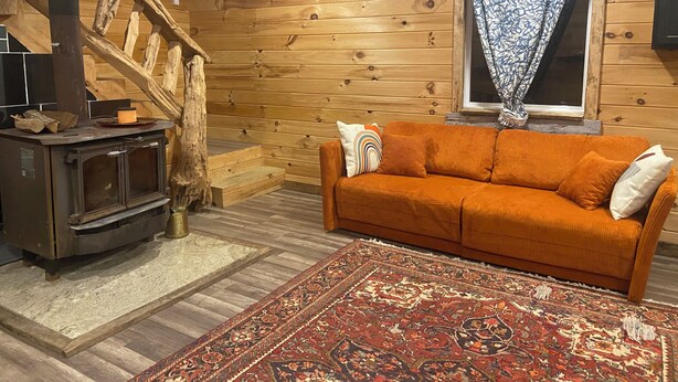 Una habitación acogedora con detalles de madera, un sofá, una alfombra estampada y una chimenea.