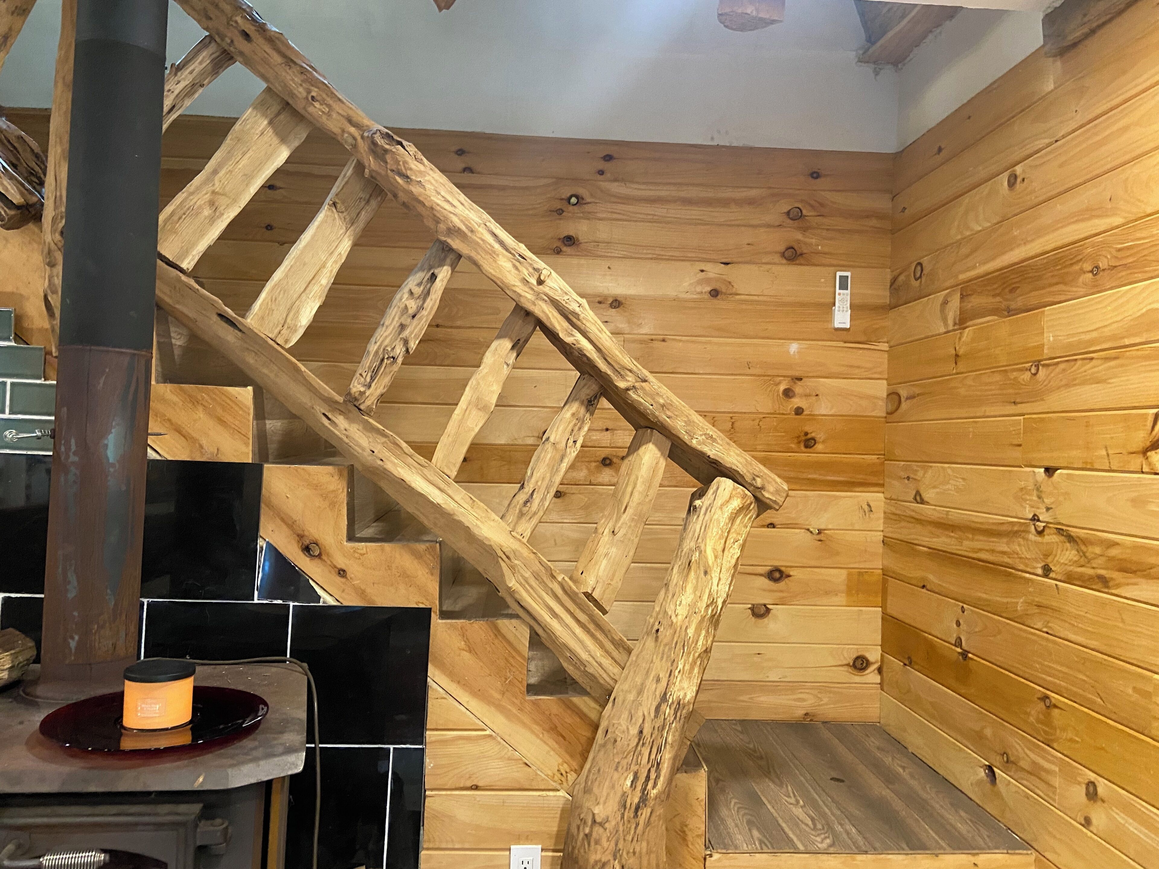 A wooden interior with a wooden staircase, a black countertop, and a stove.