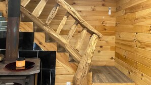 Interior de madera con una escalera de madera, una encimera negra y una estufa.