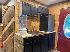 A kitchen with a built-in blender, a stainless steel refrigerator, and wooden paneling.